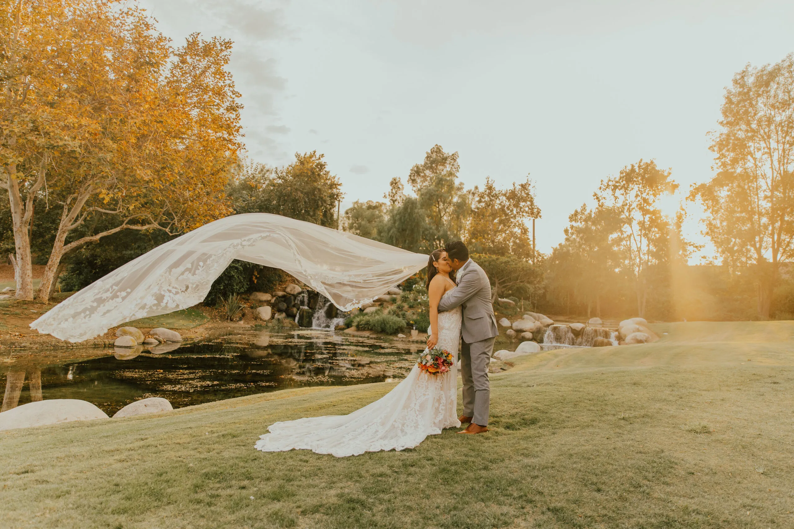 A bride on the lawn at golden hour, veil catching the light